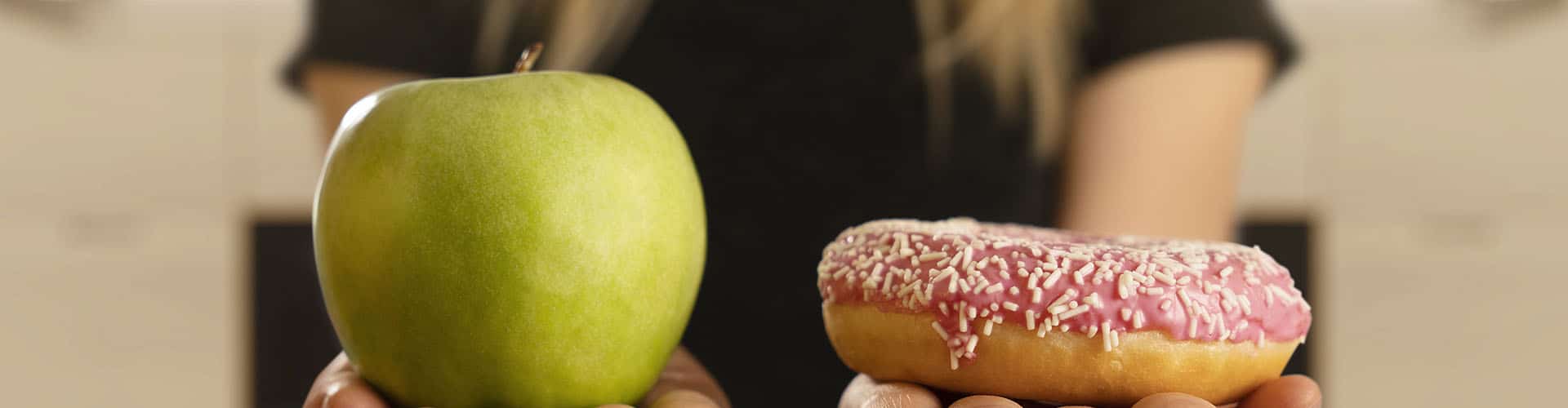 mulher compara uma maçã com um doce, um em cada mão