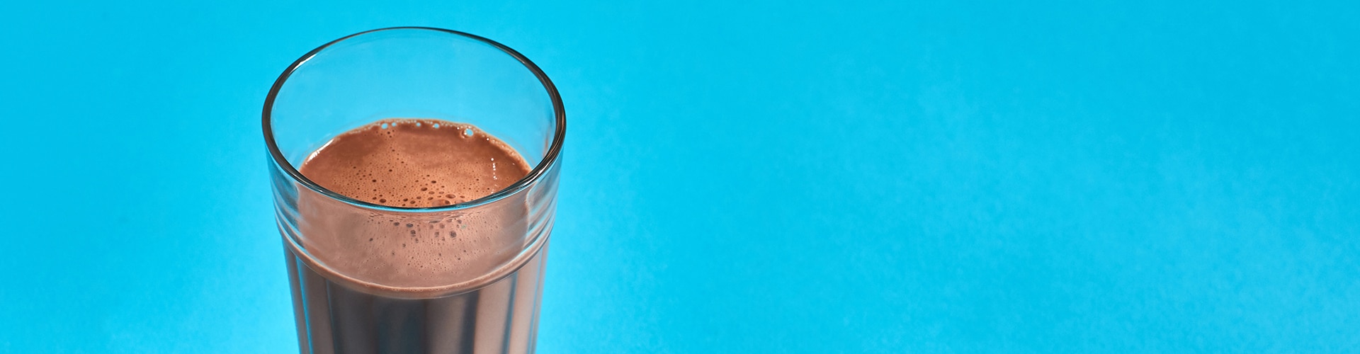 copo de milk shake de chocolate visto de cima num fundo azul