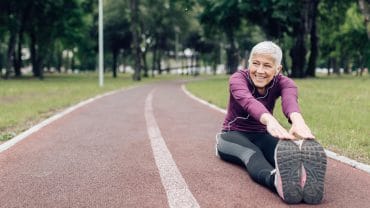 Mulher idosa feliz esticando e se preparando para correr