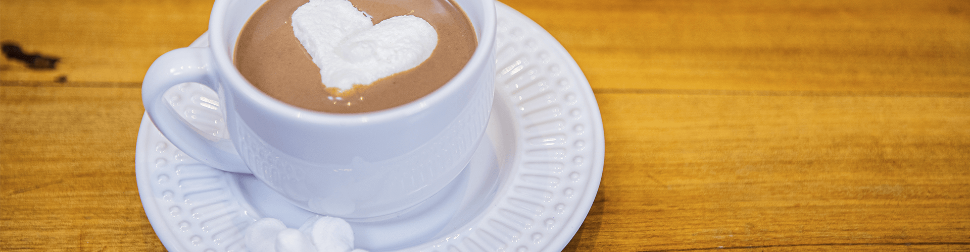 marshamallow caseiro mergulhado em uma xícara de chocolate quente.