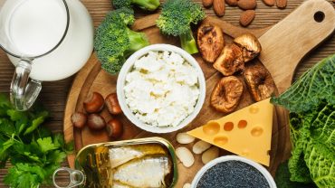 Alimentos ricos em cálcio em uma tábua de madeira em cima de uma mesa.