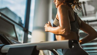 mulher na academia. Ela sua enquanto corre na esteira com o objetivo de emagrecer