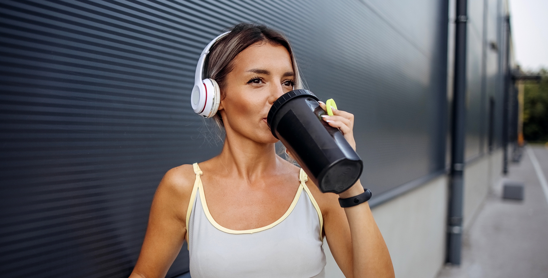 mulher de fone de ouvido tomando whey protein.