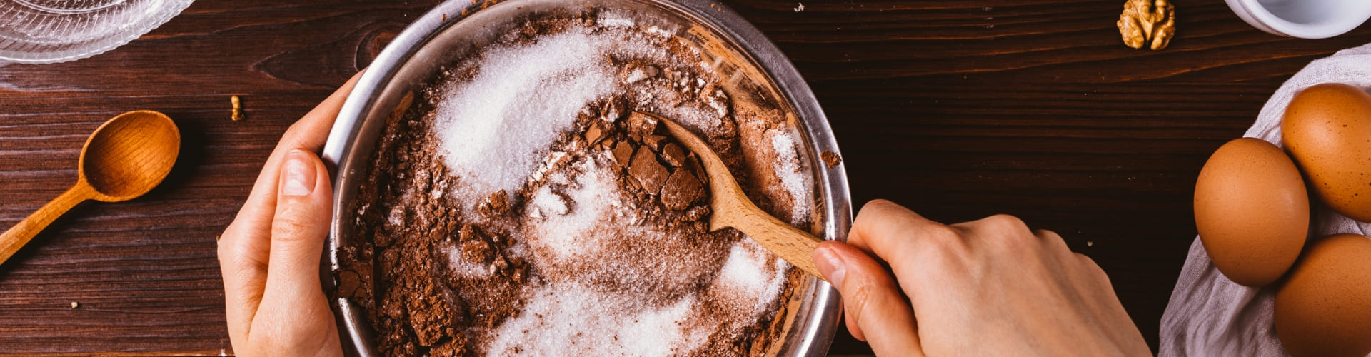 tigela com ingredientes vista de cima. A imagem mostra as mãos de uma pessoa. Uma segura a tigela e a outra mistura os ingredientes com uma colher de madeira