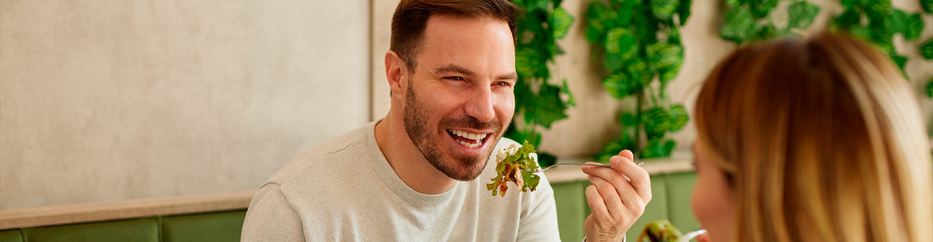 Homem e mulher compartilham uma refeição saudável com salada colorida em um ambiente agradável. Uma alimentação equilibrada, rica em proteínas, fibras e gorduras saudáveis, pode ajudar a estimular a liberação natural de GLP-1 e favorecer a saciedade
